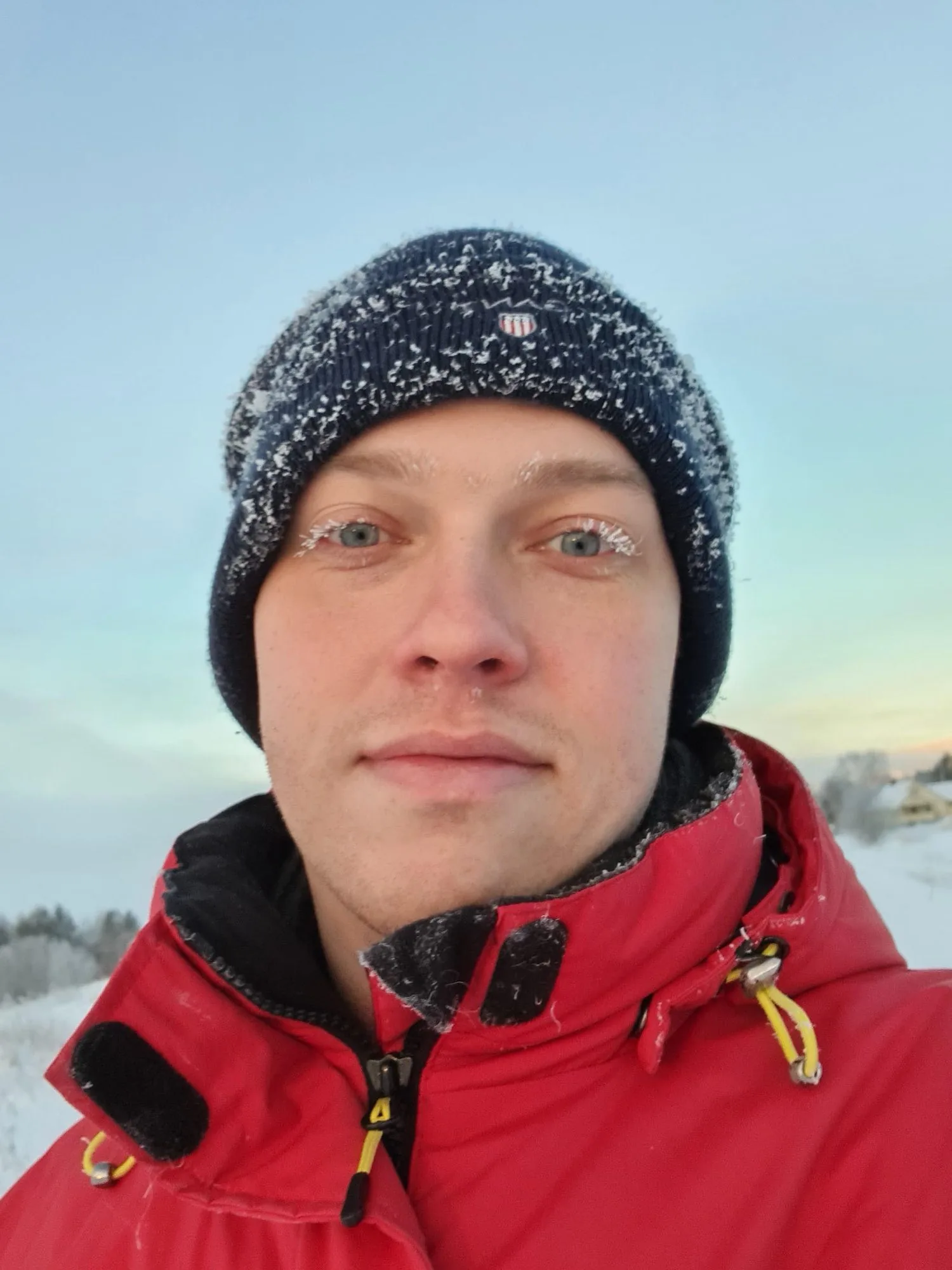 Magnus on a mountain in winter, frost on his hat and eyelashes, a pale sunrise behind him